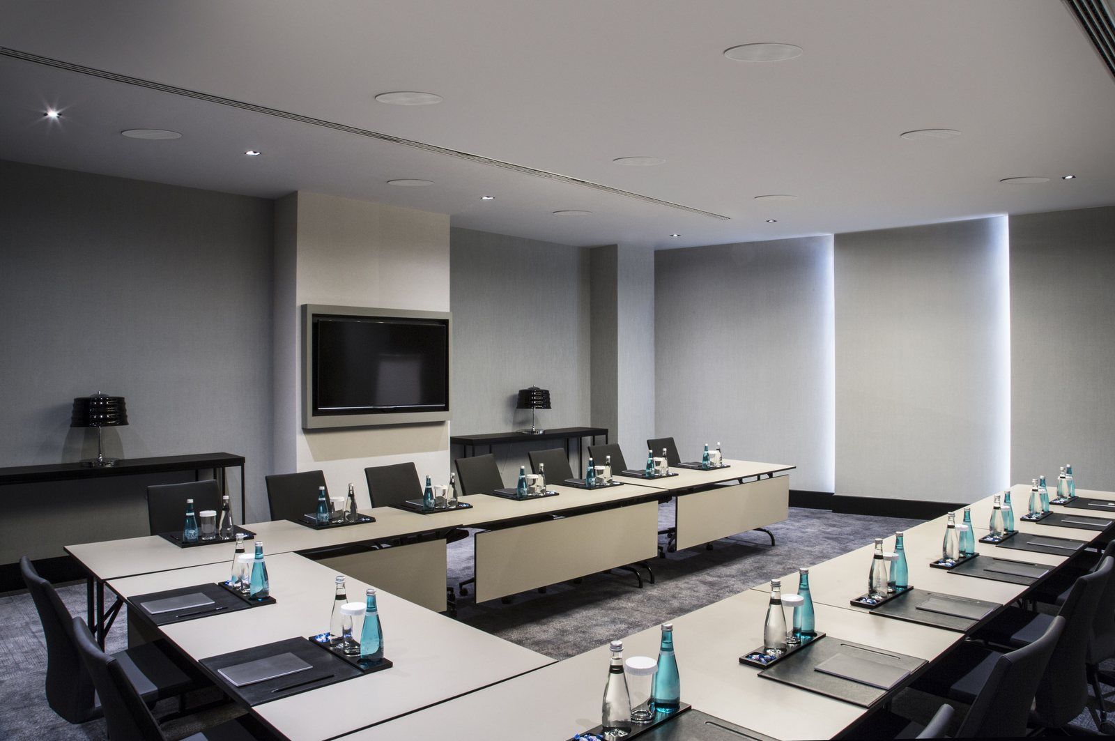 Salle de réunion en U avec écran mural et enceintes de plafond